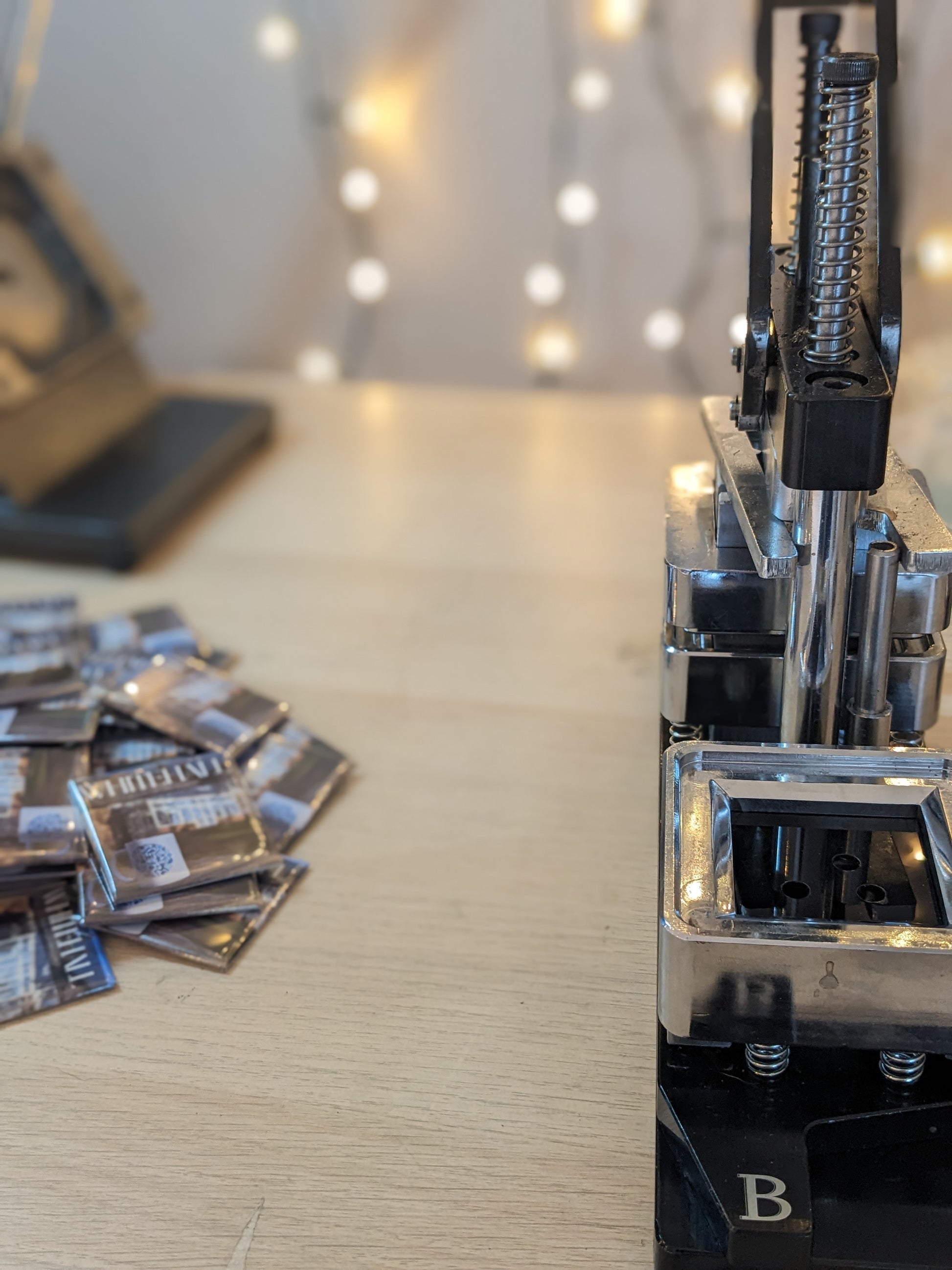 Photo of a pile of custom company logo magnets next to the magnet machine