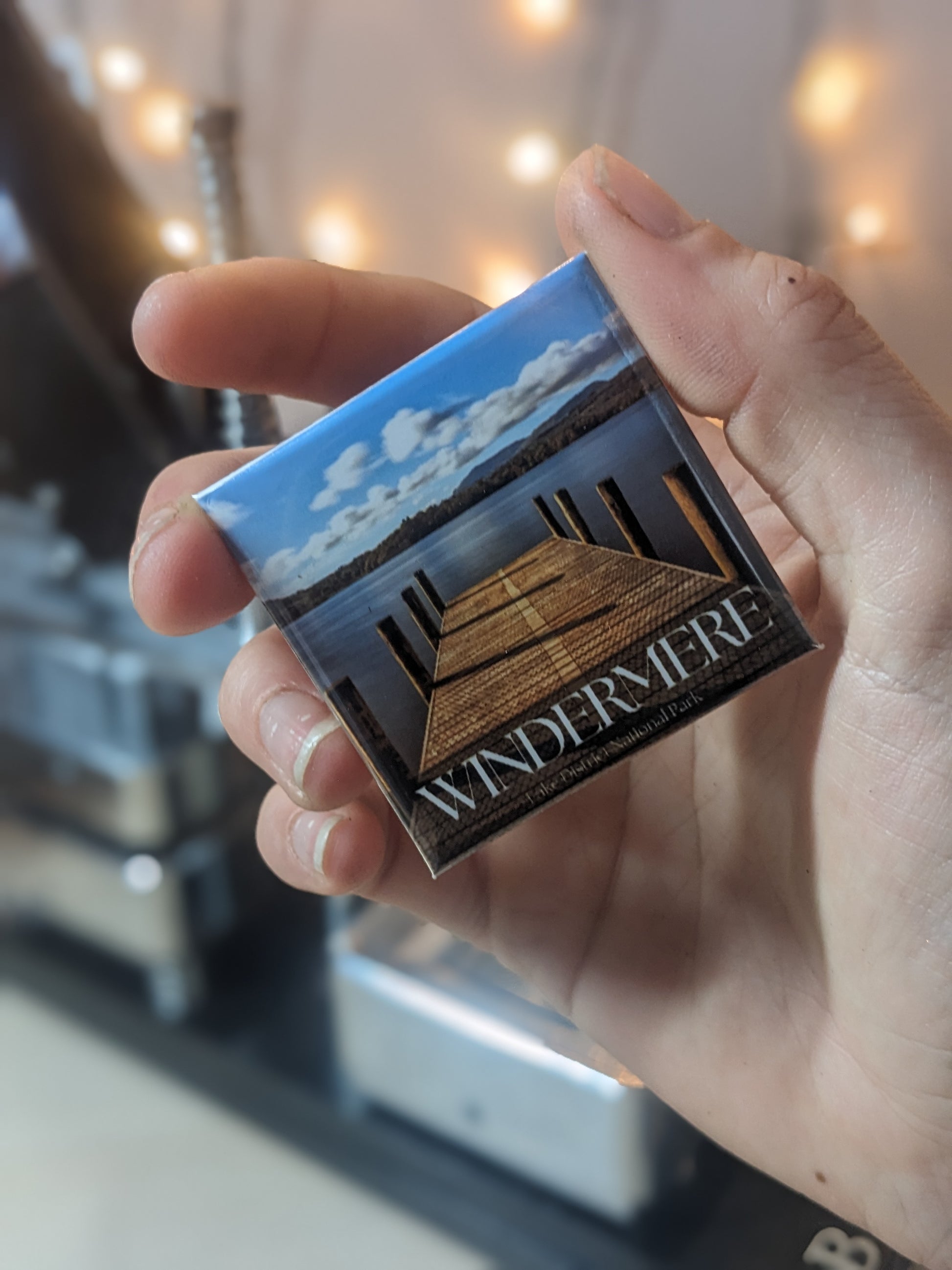 Someone holding a travel souvenir magnets of Windermere in the lake district